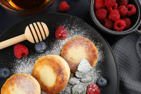 curd fritter with berries in a plate. cottage cheese fritters. Homemade cheese pancakes with fresh berries and honeyの写真素材