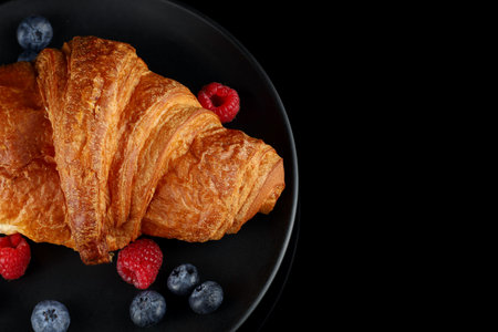 Croissant with berries on a black plateの写真素材