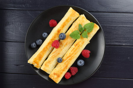 Pancakes rolls with raspberries and blueberries. Traditional breakfast and food.の写真素材