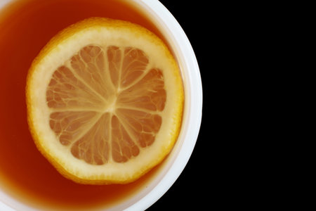 Tea with lemon in a white cup. tea on a black backgroundの写真素材