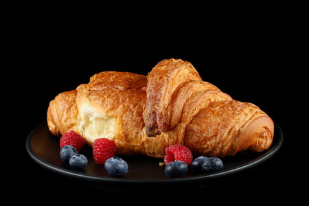 Croissant with berries on a black plateの写真素材