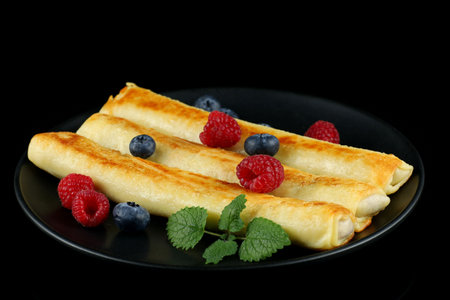 Pancakes rolls with raspberries and blueberries. Traditional breakfast and food.の写真素材