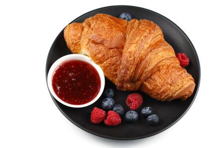 Croissant with jam and berries. traditional breakfast. Delicious breakfast - fresh croissant, jam and raspberryの写真素材