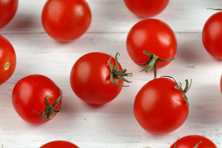 Red cherry tomatoes on a white table. Background or texture with tomatoesの写真素材