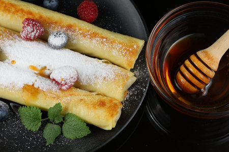 Pancakes rolls with honey and berries. Traditional thin pancakes or crepes with honey and raspberriesの写真素材