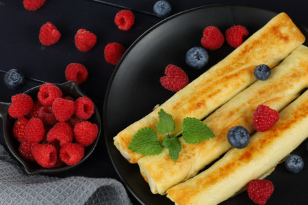 Pancakes rolls with raspberries and blueberries. Traditional breakfast and food.の写真素材