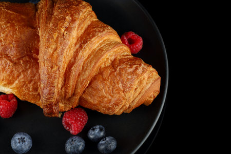 Croissant with jam and berries on a black plate. traditional breakfast.の写真素材