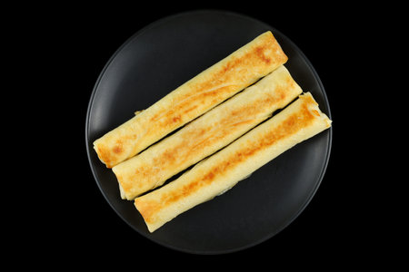 Pancake rolls on a black plate. Stuffed thin pancakes rolledの写真素材