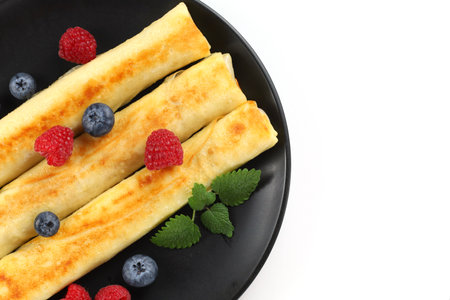 Pancakes rolls with raspberries and blueberries isolateの写真素材