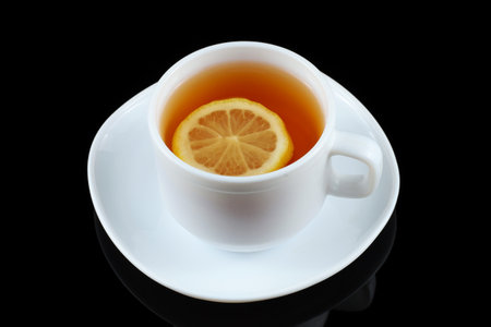 Tea with lemon in a white cup. tea on a black backgroundの写真素材