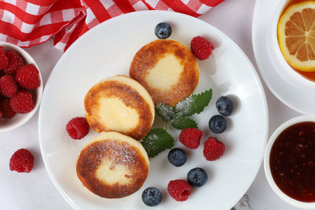 curd fritter with berries in a plate. Cottage cheese fritters on a white plate.の写真素材