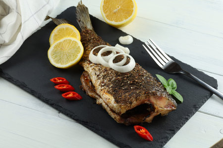 Fried carp fish with vegetables, tomatoes and lemon. Delicious fried fishの写真素材