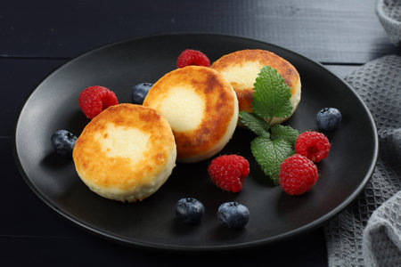 curd fritter with berries in a plate. cottage cheese fritters.の写真素材