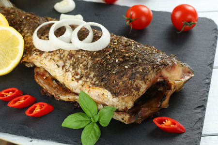 Fried carp fish on the table. Baked fish with vegetablesの写真素材