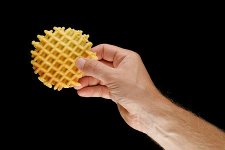 Belgian waffles in hand on black isolateの写真素材