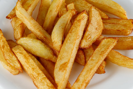 French fries on a white plate. Potatoes fries in the plate isolated on blackの写真素材