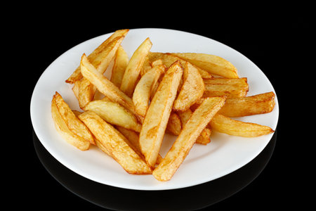 French fries on a white plate. Potatoes fries in the plate isolated on blackの写真素材
