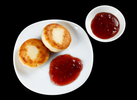 curd fritters in a plate with raspberry jam on blackの写真素材