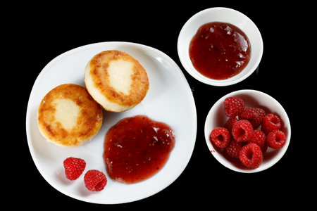 curd fritters in a plate with raspberry jam. Cottage cheese pancakes or syrniki with raspberriesの写真素材