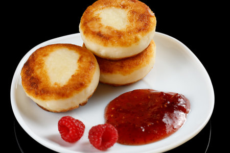 curd fritters in a plate with raspberry jam. Pancakes with jam on a plateの写真素材