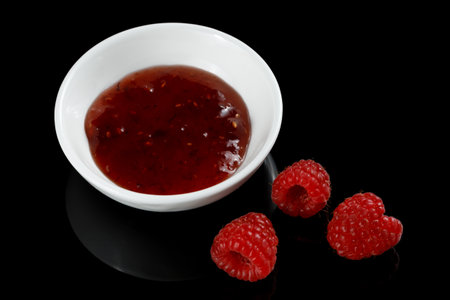 raspberries and jam on black. Jar with delicious raspberry jam. Raspberries and Jellyの写真素材