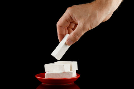 lozenge in hand. A hand takes a white vanilla pastille sweet.の写真素材