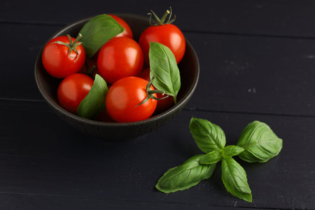Tomatoes and basil in a bowl. Fresh cherry tomatoes on a plate and basil leavesの写真素材