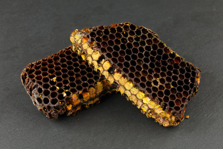 Bee pollen in honeycomb. Bee bread isolated on a black background.の写真素材