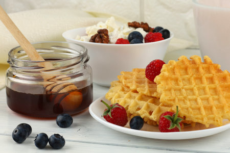 Delicious food with waffles, honey and homemade cheese with berriesの写真素材