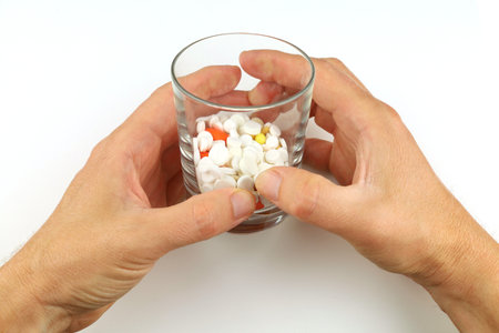 A glass with pills in his handsの写真素材