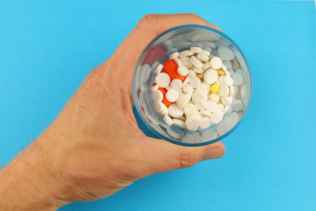 A glass with pills in his handsの写真素材