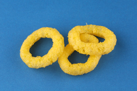 Corn rings. Yellow snacks blue backgroundの写真素材