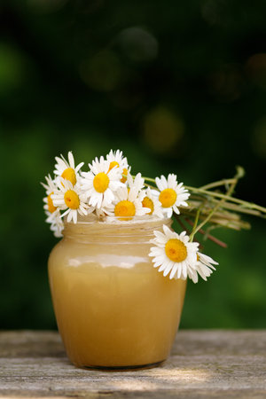Honey in a jar on the pass. Jar of honey with flowersの写真素材