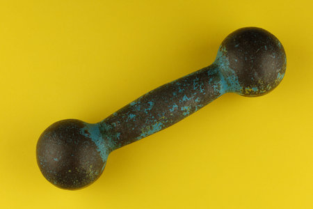 Old dumbbell 1 kg on yellow backgroundの写真素材