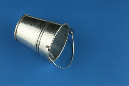 Empty metal bucket on a blue backgroundの写真素材