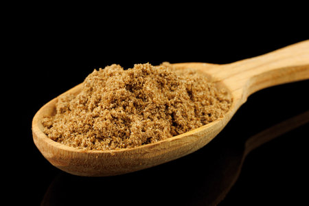 Ground coriander seasoning in a wooden spoon black backgroundの写真素材