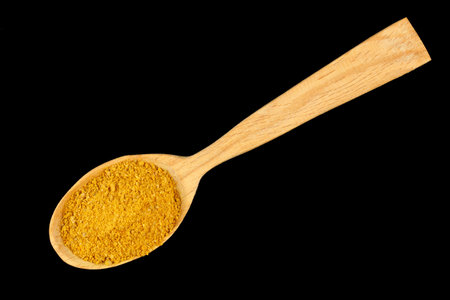 Curry powder seasoning in a wooden spoon black backgroundの写真素材