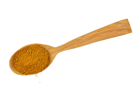 Curry powder seasoning in a wooden spoon isolateの写真素材