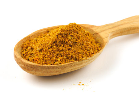 Curry powder seasoning in a wooden spoon isolateの写真素材