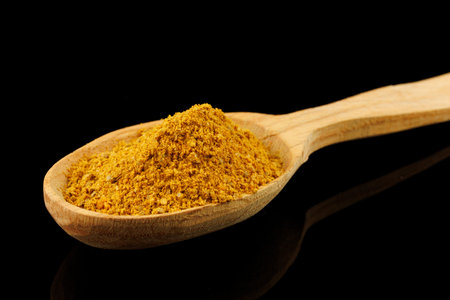 Curry powder seasoning in a wooden spoon black backgroundの写真素材