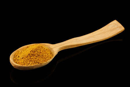 Curry powder seasoning in a wooden spoon black backgroundの写真素材