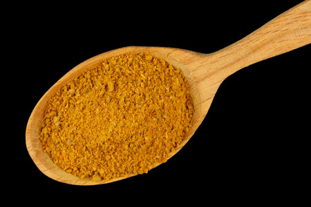 Curry powder seasoning in a wooden spoon black backgroundの写真素材