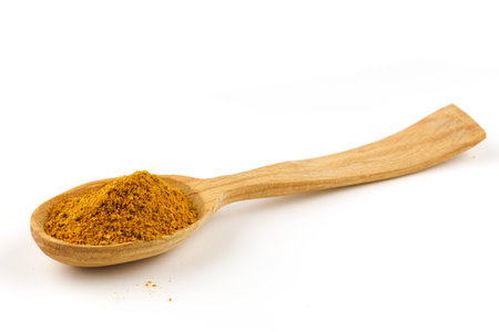 Curry powder seasoning in a wooden spoon isolateの写真素材