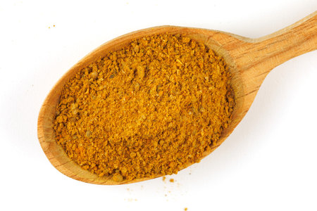 Curry powder seasoning in a wooden spoon isolateの写真素材