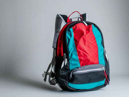 Side angle of a teal and red backpack on a white background.の素材