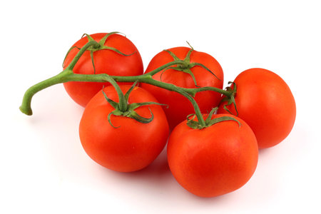 Five ripe red tomatoes sit together on a clean white background, showing their glossy texture and bright green vine.の写真素材