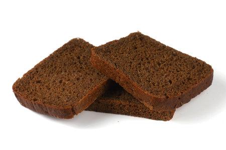 Three slices of rye bread are stacked on a white surface showing their rich color and texture.の写真素材