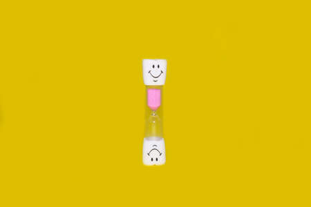 Childrens hourglass on a bright yellow backgroundの写真素材