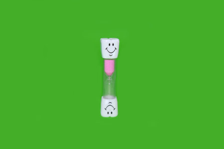 Childrens hourglass on a bright green backgroundの写真素材
