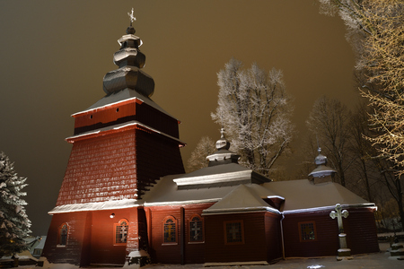Beautiful illuminated wooden church photography  in the night  winter full of snow Tylicz Polandの写真素材